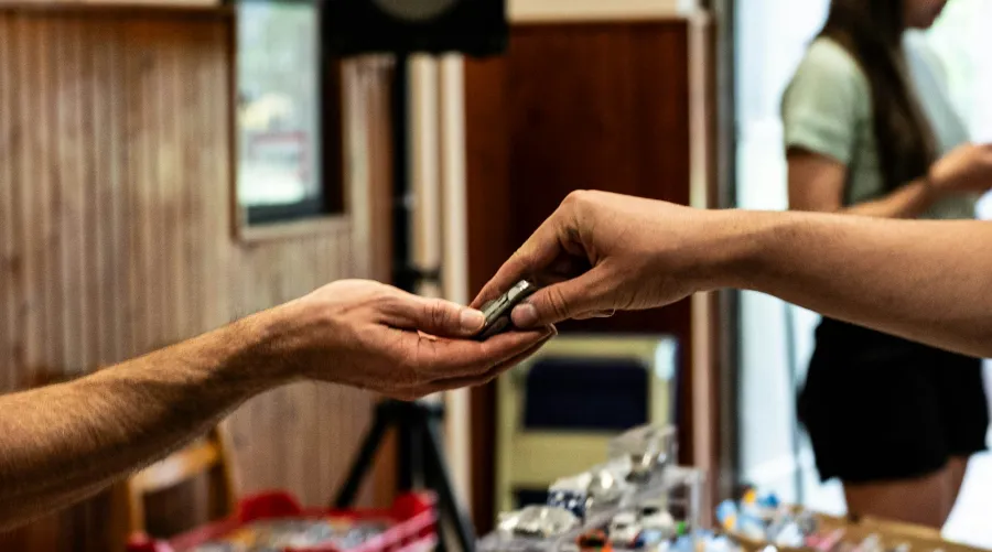 Eine Hand übergibt einer anderen Hand einen kleinen Gegenstand.